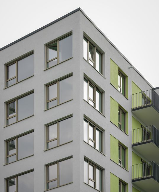 The image shows a row of multi-storey terraced houses constructed with brick and stone, featuring numerous sash windows with white frames and small front gardens enclosed by black metal railings. The 